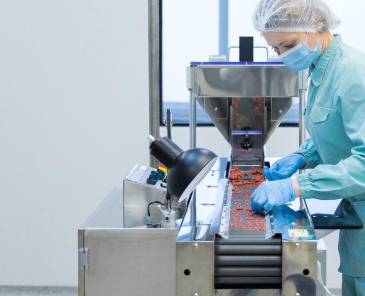 Pharmaceutical technician in sterile environment working on production of pills at pharmacy factory